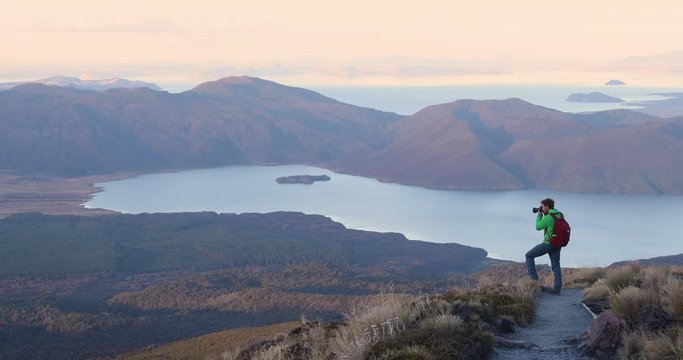 Travel Photographer Hiker and Influencer Taking Landscape photograph on Mountain on New Zealand on Wanaka hike to Roys Peak. Hiking man is photographing amazing nature on New Zealand. 59.94 FPS.