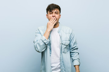 Young hispanic cool man yawning showing a tired gesture covering mouth with hand.