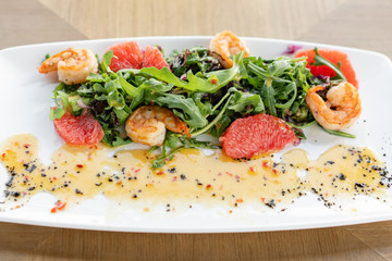 Delicious dish with grilled shrimps, slice grapefruit and arugula salad and spicy fried prawns. Restaurant menu, natural and organic food concept.