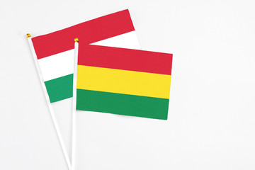 Bolivia and Hungary stick flags on white background. High quality fabric, miniature national flag. Peaceful global concept.White floor for copy space.