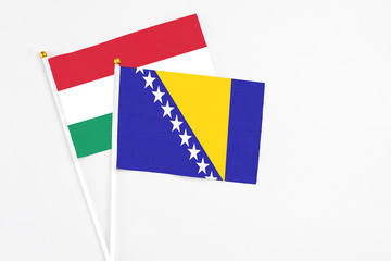 Bosnia Herzegovina and Hungary stick flags on white background. High quality fabric, miniature national flag. Peaceful global concept.White floor for copy space.