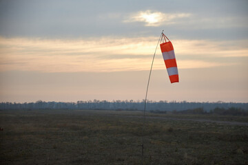 Fototapeta na wymiar Indicator of speed and wind strength at the aerodrome in the form of a conical striped sleeve.