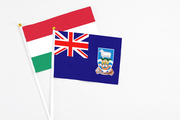 Fototapeta premium Falkland Islands and Hungary stick flags on white background. High quality fabric, miniature national flag. Peaceful global concept.White floor for copy space.