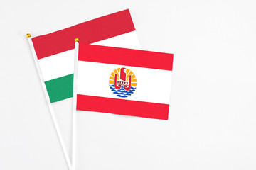 French Polynesia and Hungary stick flags on white background. High quality fabric, miniature national flag. Peaceful global concept.White floor for copy space.