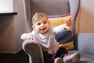 Cute baby girl sitting on big armchair and smile