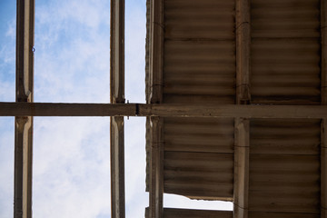 Partially destroyed roof of an old building through which a blue sky is visible.