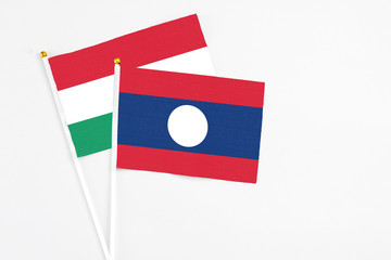 Laos and Hungary stick flags on white background. High quality fabric, miniature national flag. Peaceful global concept.White floor for copy space.