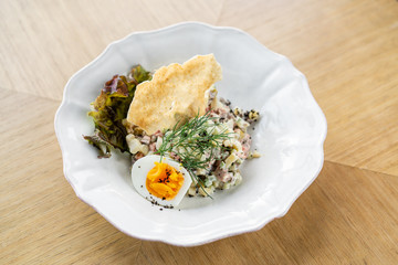 Russian traditional salad Olivier with vegetables and meat. Salad on a plate on a wooden plate. Menu restaurant. Russian traditional salad