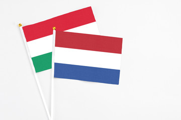 Netherlands and Hungary stick flags on white background. High quality fabric, miniature national flag. Peaceful global concept.White floor for copy space.