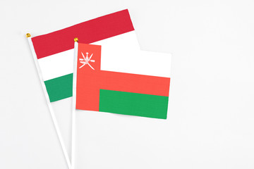Oman and Hungary stick flags on white background. High quality fabric, miniature national flag. Peaceful global concept.White floor for copy space.