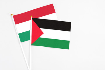 Palestine and Hungary stick flags on white background. High quality fabric, miniature national flag. Peaceful global concept.White floor for copy space.