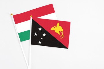 Papua New Guinea and Hungary stick flags on white background. High quality fabric, miniature national flag. Peaceful global concept.White floor for copy space.