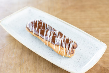 Traditional french eclairs with chocolate. Cake decorated with chocolate cream on top of are on a wooden table