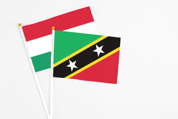 Saint Kitts And Nevis and Hungary stick flags on white background. High quality fabric, miniature national flag. Peaceful global concept.White floor for copy space.