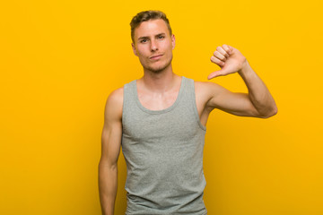 Young caucasian sport man showing a dislike gesture, thumbs down. Disagreement concept.