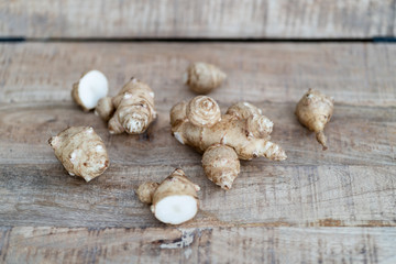 Root of topinabur on a wooden background. Jerusalem artichokes called sunroot.