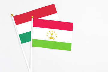 Tajikistan and Hungary stick flags on white background. High quality fabric, miniature national flag. Peaceful global concept.White floor for copy space.
