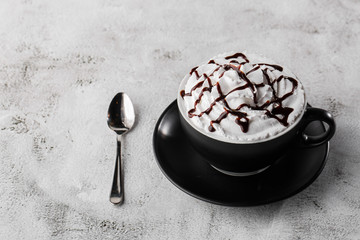 Coffe with whipped cream and chocolate topping. Iced frappuccino in dark cup isolated on bright marble background. . Advertising for cafe menu. Coffee shop menu. Horizontal photo.