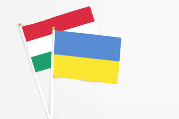 Ukraine and Hungary stick flags on white background. High quality fabric, miniature national flag. Peaceful global concept.White floor for copy space.