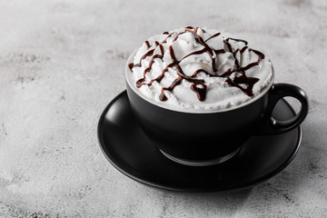 Coffe with whipped cream and chocolate topping. Iced frappuccino in dark cup isolated on bright marble background. . Advertising for cafe menu. Coffee shop menu. Horizontal photo.