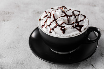 Coffe with whipped cream and chocolate topping. Iced frappuccino in dark cup isolated on bright marble background. . Advertising for cafe menu. Coffee shop menu. Horizontal photo.