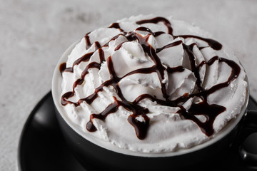 Coffe with whipped cream and chocolate topping. Iced frappuccino in dark cup isolated on bright marble background. . Advertising for cafe menu. Coffee shop menu. Horizontal photo.