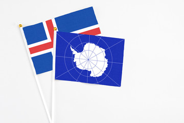 Antarctica and Iceland stick flags on white background. High quality fabric, miniature national flag. Peaceful global concept.White floor for copy space.