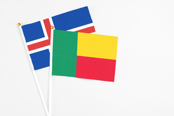 Benin and Iceland stick flags on white background. High quality fabric, miniature national flag. Peaceful global concept.White floor for copy space.