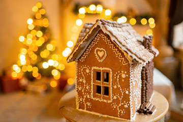 Gingerbread house, concept holiday of Christmas and Happy new year. Defocused lights of Christmas tree. Morning in the bright living room. Holiday mood.