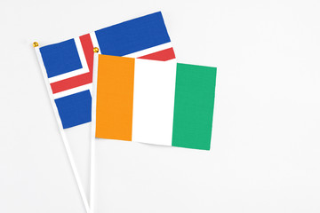 Cote D'Ivoire and Iceland stick flags on white background. High quality fabric, miniature national flag. Peaceful global concept.White floor for copy space.