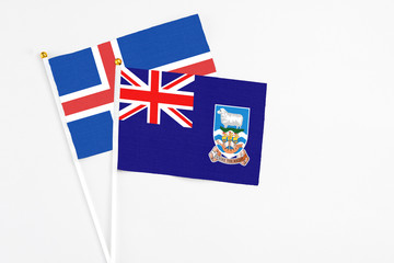 Fototapeta premium Falkland Islands and Iceland stick flags on white background. High quality fabric, miniature national flag. Peaceful global concept.White floor for copy space.