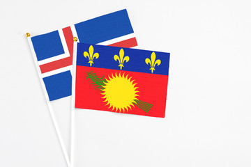 Guadeloupe and Iceland stick flags on white background. High quality fabric, miniature national flag. Peaceful global concept.White floor for copy space.