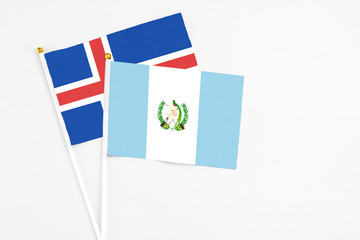 Guatemala and Iceland stick flags on white background. High quality fabric, miniature national flag. Peaceful global concept.White floor for copy space.