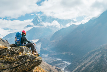 Jonge wandelaar backpacker vrouw zittend op de rand van de klif en genieten van Ama Dablam 6.812 m piek uitzicht tijdens Everest Base Camp (EBC) trekking route in de buurt van Phortse, Nepal. Actieve vakantie concept afbeelding