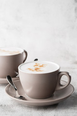 Two white cups of hot latte coffee with beautiful milk foam latte art texture isolated on bright marble background. Overhead view, copy space. Advertising for cafe menu. Vertical photo.
