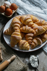bagels lie in a plate on an old wooden background, next to eggs and flour. bakery products