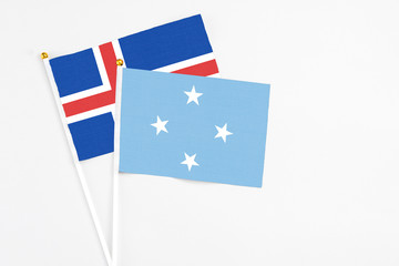 Fototapeta premium Micronesia and Iceland stick flags on white background. High quality fabric, miniature national flag. Peaceful global concept.White floor for copy space.