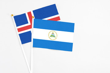 Nicaragua and Iceland stick flags on white background. High quality fabric, miniature national flag. Peaceful global concept.White floor for copy space.