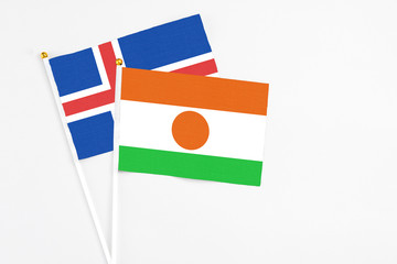 Niger and Iceland stick flags on white background. High quality fabric, miniature national flag. Peaceful global concept.White floor for copy space.