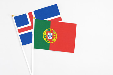 Portugal and Iceland stick flags on white background. High quality fabric, miniature national flag. Peaceful global concept.White floor for copy space.
