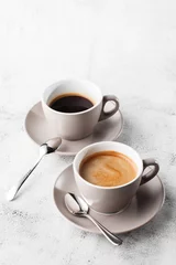 Küchenrückwand glas motiv Cafe Zwei weiße Tassen heißen schwarzen Kaffee mit Milch auf hellem Marmorhintergrund. Draufsicht, Kopienraum. Werbung für Café-Menü. Speisekarte des Cafés. Vertikales Foto.