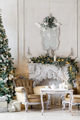 Christmas morning. Classic luxury apartments with a white fireplace, christmas tree, sofa, large windows and chandelier.