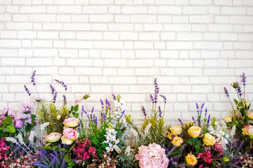 Bouquet of artificial flowers with white brick wall background.