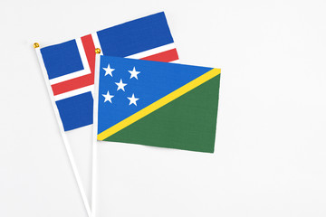 Solomon Islands and Iceland stick flags on white background. High quality fabric, miniature national flag. Peaceful global concept.White floor for copy space.