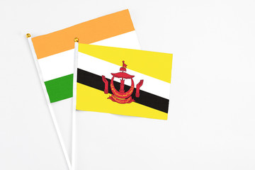 Brunei and India stick flags on white background. High quality fabric, miniature national flag. Peaceful global concept.White floor for copy space.