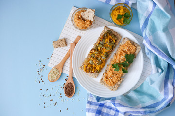 Two crackers with humus on blue background top view. Hummus sandwiches. Healthy food concept