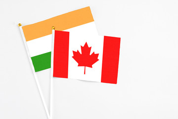 Canada and India stick flags on white background. High quality fabric, miniature national flag. Peaceful global concept.White floor for copy space.