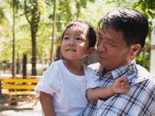 Asian child boy and grandfather smiling together outdoor park. Grandpa and cute grandchild in happy moment with relax face in happy family time day.