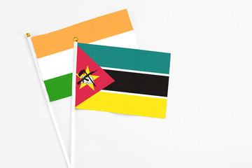 Mozambique and India stick flags on white background. High quality fabric, miniature national flag. Peaceful global concept.White floor for copy space.