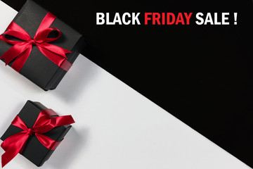 Top view of black christmas gift boxes with red ribbon and text on black and white background with copy space for text., black friday advertisement.